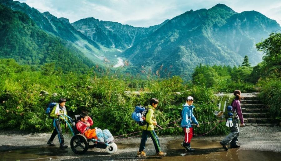 大自然の中を散策する車いすの人と徒歩の人